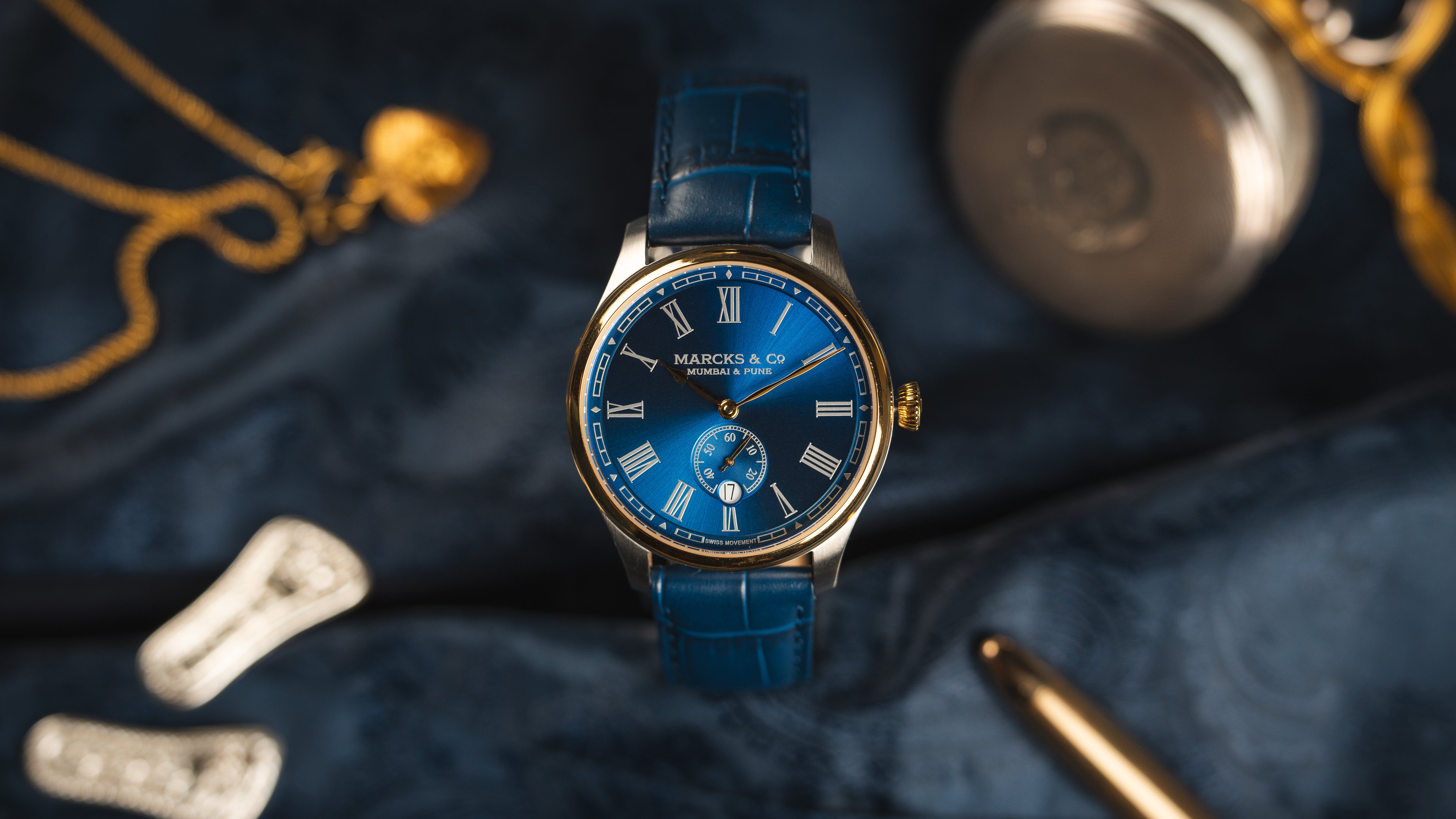 Blue watch with gold and silver accents on a dark textured surface