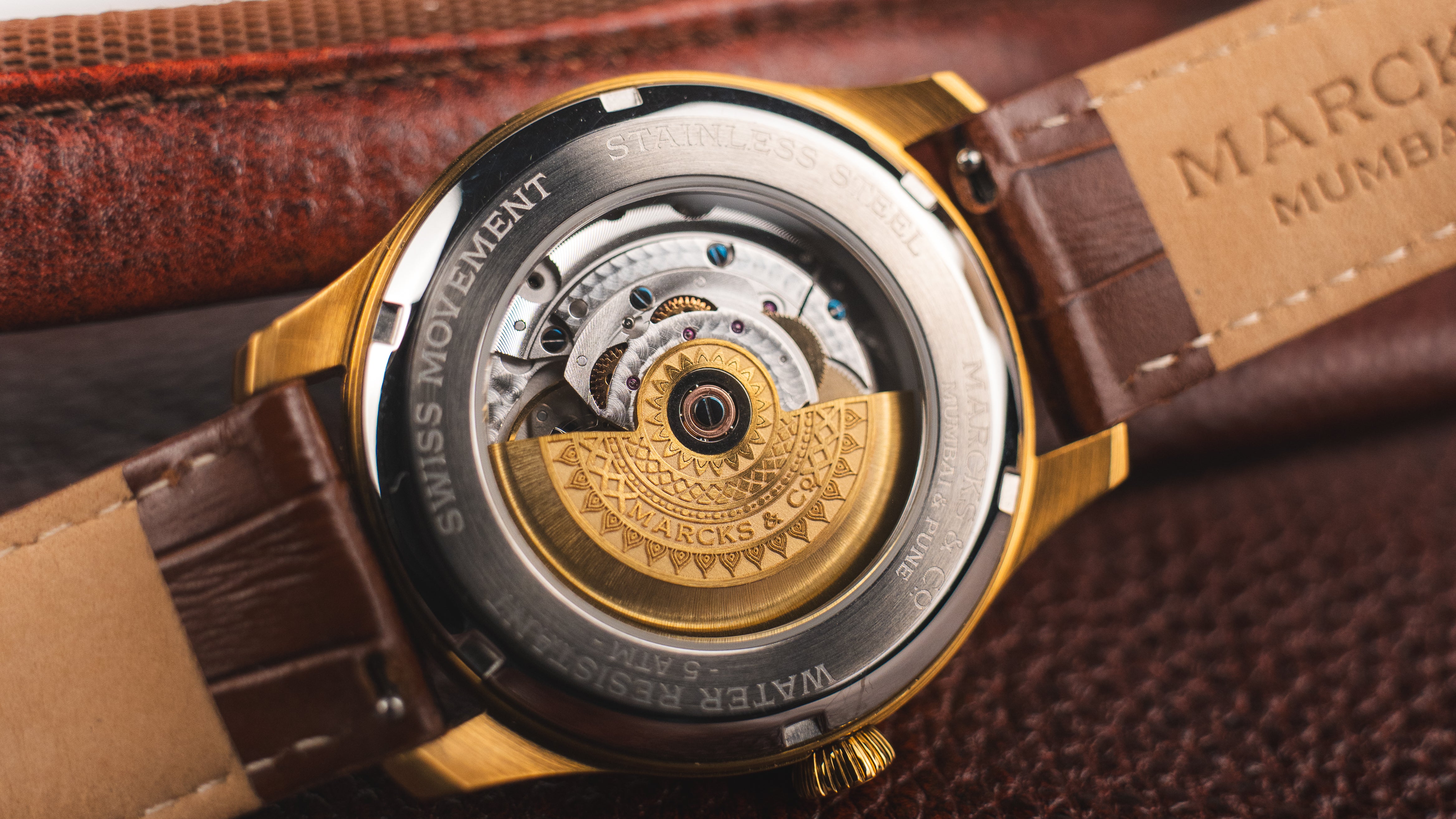 Close-up of a watch with a visible Swiss movement on a brown leather strap.